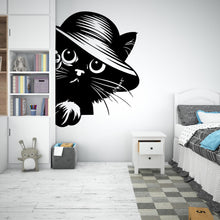 Load image into Gallery viewer, May include: Black and white silhouette of a cat wearing a hat, peeking around a corner. The cat has large eyes and a playful expression. The image is a wall decal.